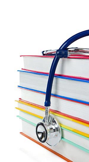 Stethoscope draped over a stack of books. Naturopathic Physicians complete a four year postgraduate program at an approved Naturopathic Medical College
